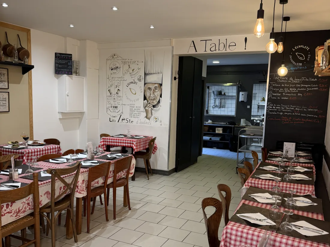 Photo de la grande salle, ses tables en nappes vichy, l'ardoise et le mur « À Table ! », pour un repas de groupe à la Brasserie l'Échalote, Lyon 7