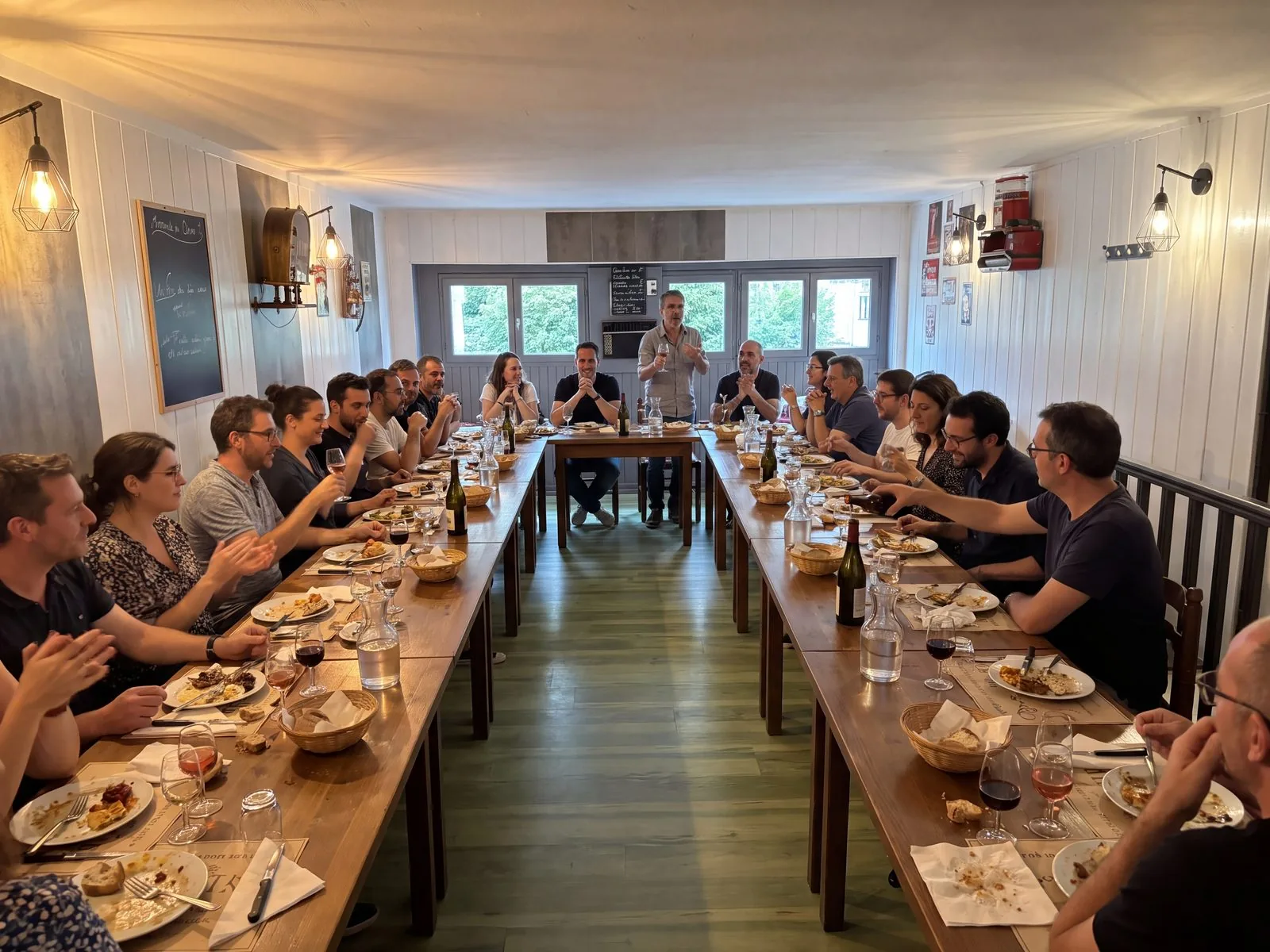 Photo de la salle à l'étage privatisée, tables dressées en fer à cheval et convives qui lèvent leur verre, à la Brasserie l'Échalote, la meilleure salle privée de Lyon 7 pour une privatisation, à Gerland, près du métro Jean Jaurès